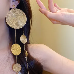 Close-up showing the intricate texture of golden round tassel drop earrings on a model