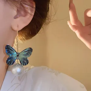 Detailed view of an elegant blue butterfly wing earring with a textured pearl bead pendant