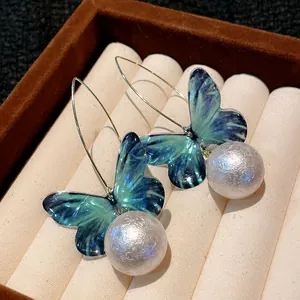 Macro view of blue butterfly wings and textured pearl earrings in a velvet display tray