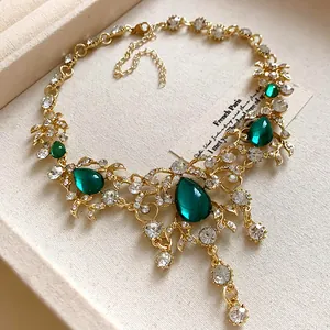 Macro view of vintage gold-toned necklace with green water-drop gems and rhinestones