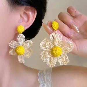 Handmade vacation style woven flower earrings with yellow centers and cream petals
