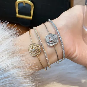 Exquisite close-up of sparkling zircon flower bangles and crystal bracelets on a wrist.