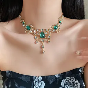 Close-up view of a vintage palace style necklace featuring green teardrop gems and rhinestones