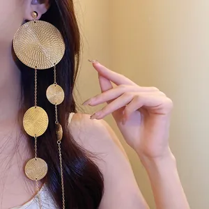 Detail of gold textured circle fringe earrings worn by a model