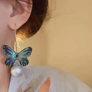 Close-up detail of an elegant fairy-style butterfly and pearl drop earring on model ear