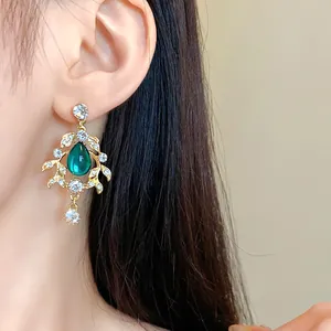 Close-up of vintage emerald green waterdrop earring with leaf design and rhinestones