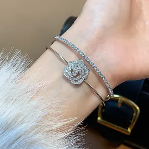 Detailed view of silver-toned open bangle featuring a zircon camellia flower and tennis band