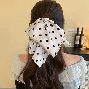 Detailed view of a large white bow hair clip with black polka dots on wavy hair