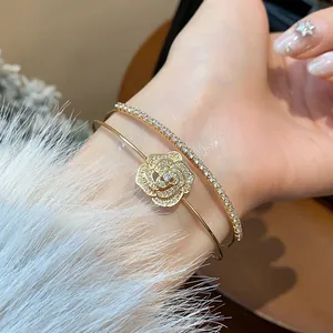 Close-up of double-layer zircon flower bangle in gold finish on a wrist.