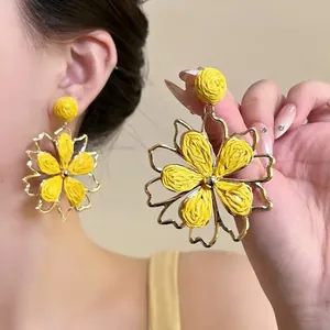Detailed macro view of yellow woven flower earrings with elegant gold-tone petal frames