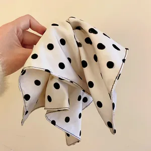 Macro detail view of white fabric-wrapped hair claw clip featuring large black polka dots