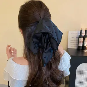 Detailed view of an elegant black polka dot bow hair claw clip worn on a model's hair