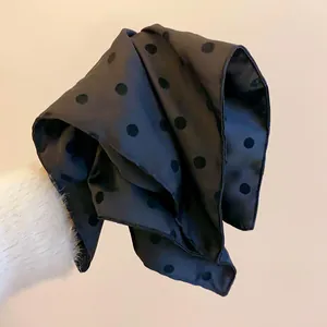 Close-up detail of black polka dot fabric hair accessory with soft texture