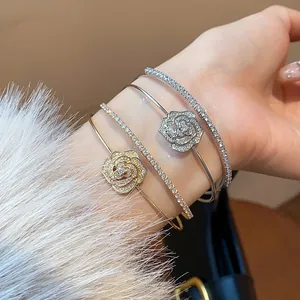 Elegant close-up of layered zircon flower open bangles and sparkling tennis bracelets.