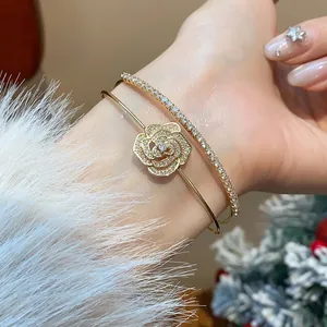 Elegant close-up of a double-layered gold bracelet set featuring a zircon pavé rose flower
