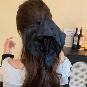 Detailed back view of long hair styled with a large black polka dot fabric bow hair clip
