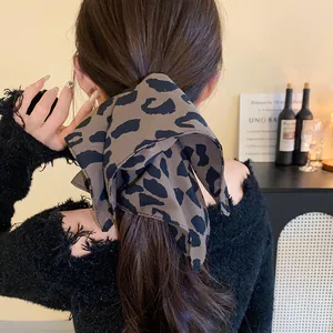 Close-up detail of a stylish leopard print fabric bow hair tie on a woman's low ponytail