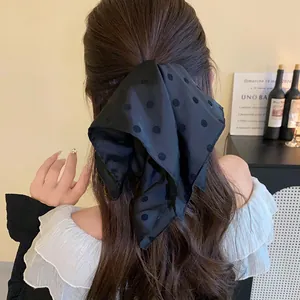 Detailed view of a large black polka dot bow hair clip styled on wavy hair