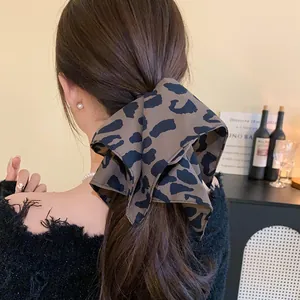 Detailed macro view of a stylish leopard print fabric bow hair tie on long brown hair
