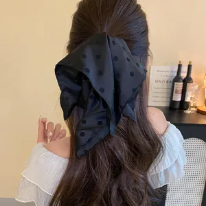 Macro view of a black polka dot ribbon hair bow worn by a woman for an elegant style