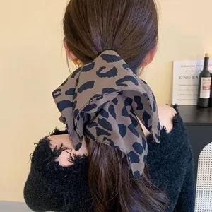 Detailed view of a leopard print fabric bow hair tie on a woman's dark brown hair