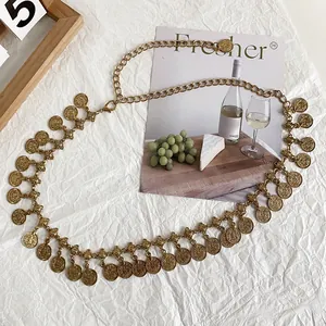 Close-up of ethnic gold waist chain featuring round coin tassels on a white background