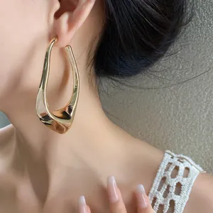 Detailed close-up of a minimalist golden geometric irregular hollow earring on ear.