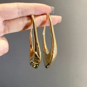Minimalist geometric irregular hollow earrings in gold finish held between fingers
