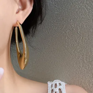 Detailed view of minimalist gold irregular geometric hollow earring on model's ear