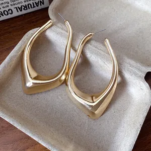 Detailed macro view of high-end gold geometric irregular hollow earrings in cardboard box