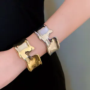 Detailed view of liquid-style irregular metallic open cuff bracelets in gold and silver.