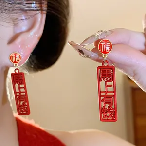Detailed view of red Chinese 'Fu' and wealth blessing oil-drip drop stud earrings