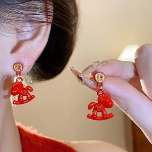 Detail view of red enamel rocking horse earrings with Chinese fortune character