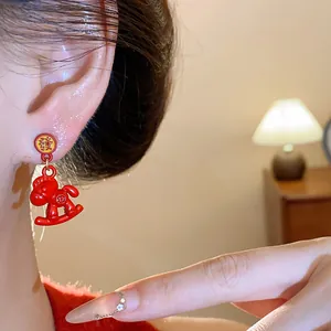 Close-up detail of red enamel rocking horse ear studs worn on ear, festive jewelry