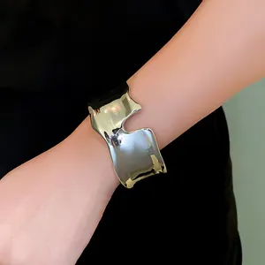 Macro detail of a minimalist silver liquid irregular open cuff bracelet on wrist