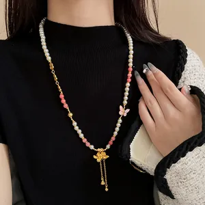 Dettaglio di una collana di perle lunga in stile cinese con loto e farfalla su una modella