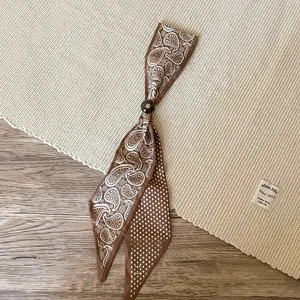 Detail view of a retro brown silk scarf necklace with paisley and polka dot prints