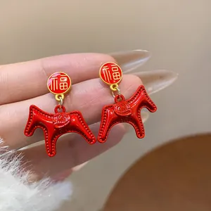 Macro view of Chinese New Year style red horse earrings featuring gold 'Fu' character detail