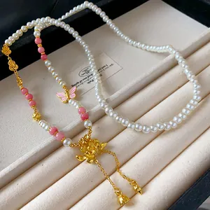 Dettaglio della collana lunga di perle artificiali con loto e farfalla retrò