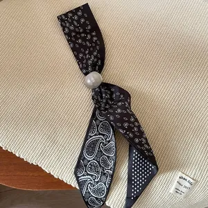 Detail view of a vintage fabric scarf necklace featuring black paisley and polka dot prints