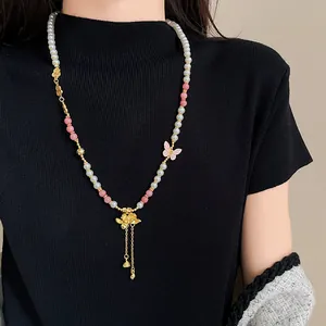 Dettaglio di una collana di perle in stile cinese con ciondolo a loto e farfalla