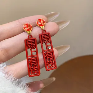 Macro detail of red drop oil earrings featuring traditional Chinese lucky characters