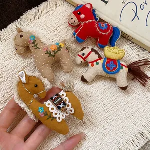 Detail view of four colorful handmade fabric horse brooches with floral embroidery.