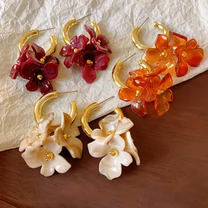 Close-up of vintage French acrylic flower earrings in red, amber, and beige colors.