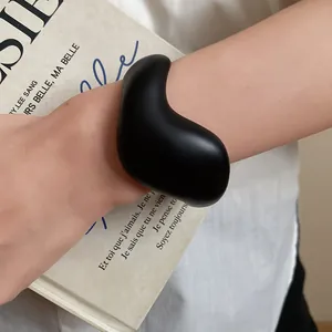 Close-up of black minimalist organic shaped acrylic cuff bracelet worn on model's wrist