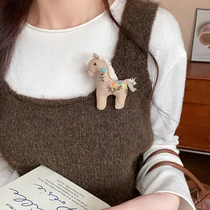 Close-up of a handmade fabric horse brooch with floral embroidery on a knitted vest