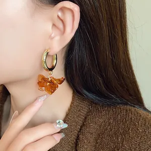 Detail view of vintage amber acrylic flower hoop earrings on a female model's ear