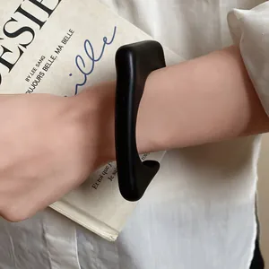 Detailed macro shot of a minimalist chunky matte black acrylic open cuff bracelet
