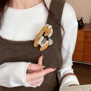 Detail view of a cute fabric horse brooch with floral embroidery on a knit vest