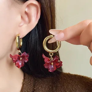 Close-up detail view of vintage French style red acrylic flower hoop earrings on ear.